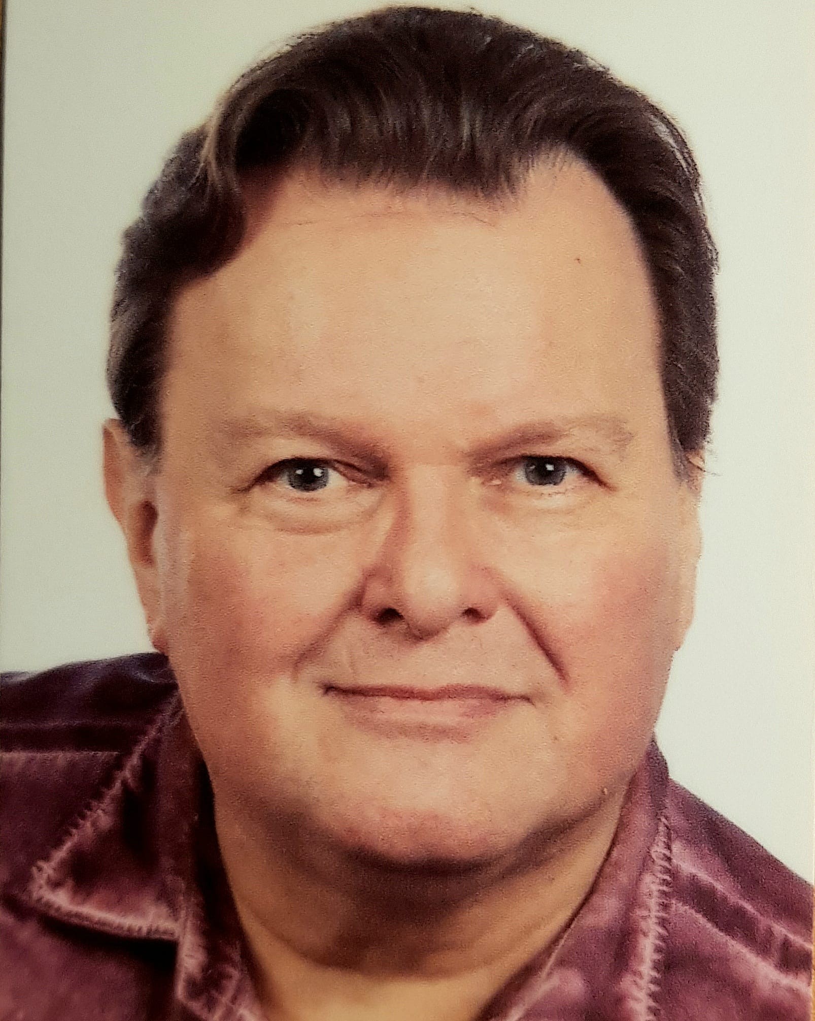 Jörg Schörner Portrait von Jörg Schörner in purpurnem Hemd vor weißem Hintergrund.