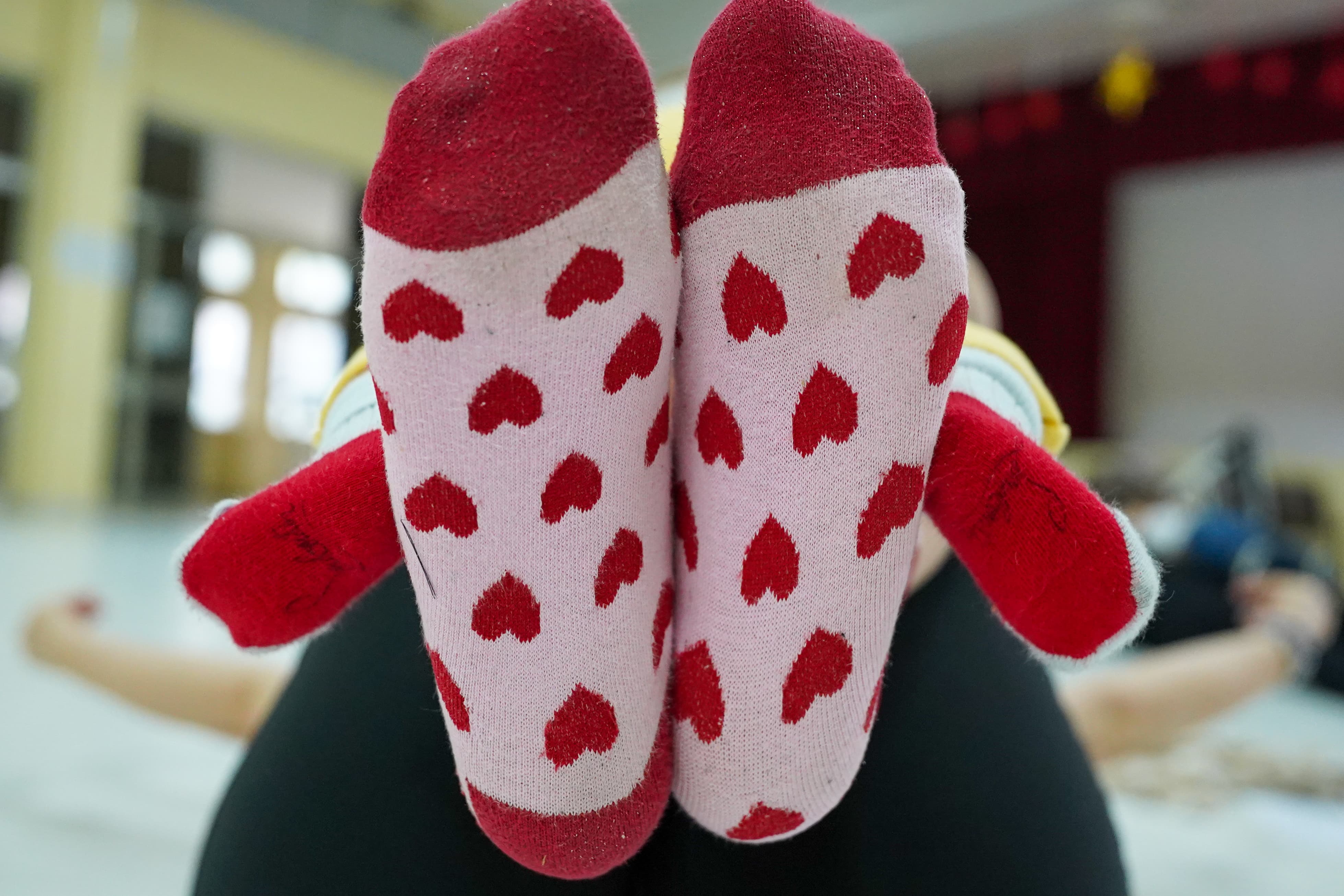 Zwei Füße in rot-rosa Socken mit Herzmotiv und zwei Babyfüße in roten Socken