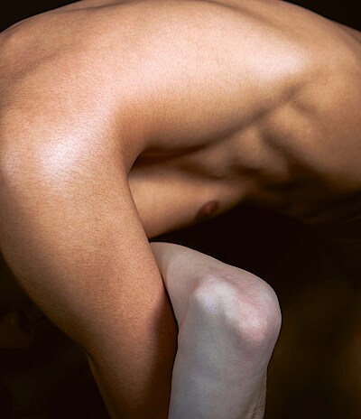 Nahaufnahme eines männlichen Torsos, der vornüber gebeugt ist, verschlungen mit einem Arm einer anderen Person