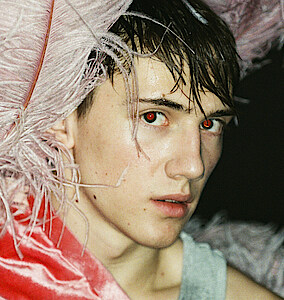 Tänzer Matthys de Beer trägt pinkfarbenen Federkopfschmuck und blickt verhalten in die Kamera.