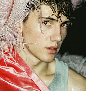 Tänzer Matthys de Beer trägt pinkfarbenen Federkopfschmuck und blickt verhalten in die Kamera.