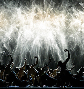 Ensemble in kniender Pose vor Lichtschauspiel.