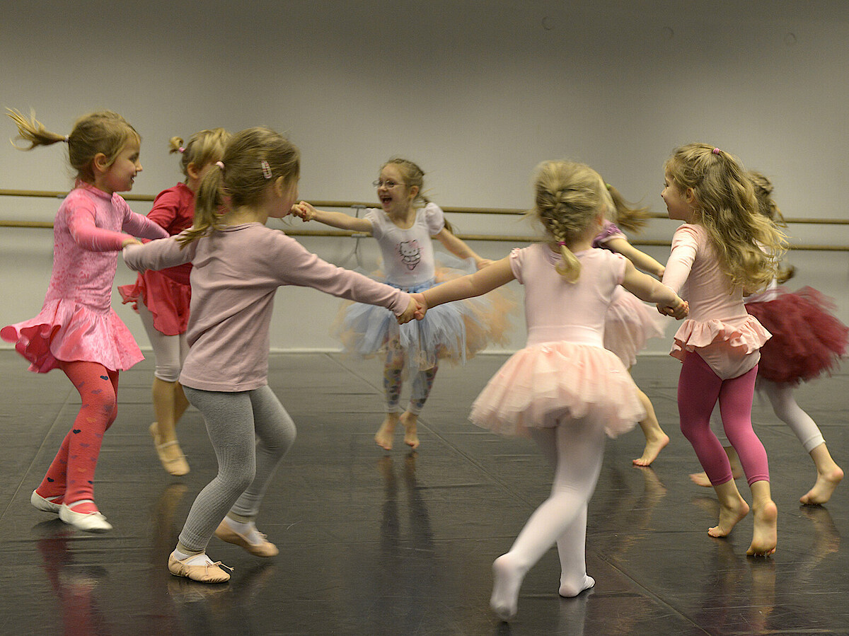 Girls with colourful skirts are dancing together in a circle