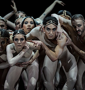 Tänzer*innen-Gruppe in hautfarbenen Kostümen, nach vorne gebeugt, blicken konzentriert in Richtung Kamera in Sharon Eyals "2 Chapters Love"