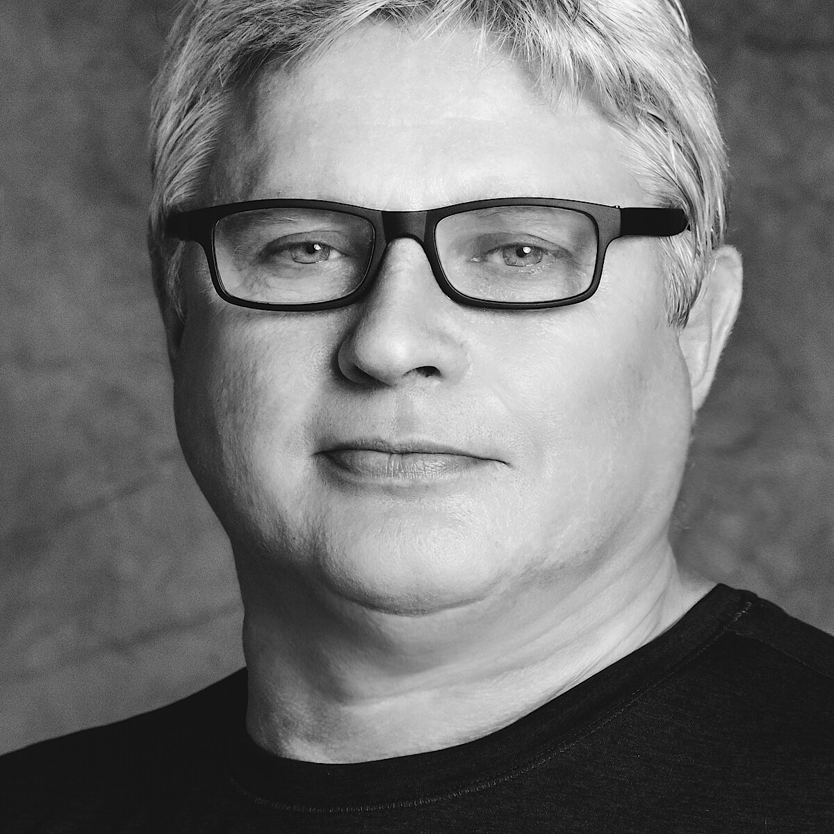 Schwarz-weiß-Portrait von Yuri Possokhov in schwarzem Shirt und schwarzer Brille.
