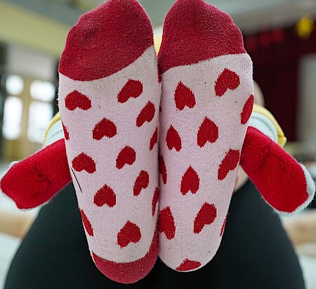 Futura Danza 2 Zwei Füße in rot-rosa Socken mit Herzmotiv und zwei Babyfüße in roten Socken