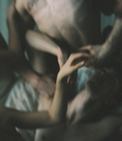 Unscharfe Körper liegen ineinander verschränkt auf dem Boden.