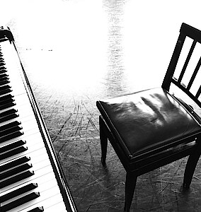Klaviertasten und leerer Stuhl, in schwarz-weiß