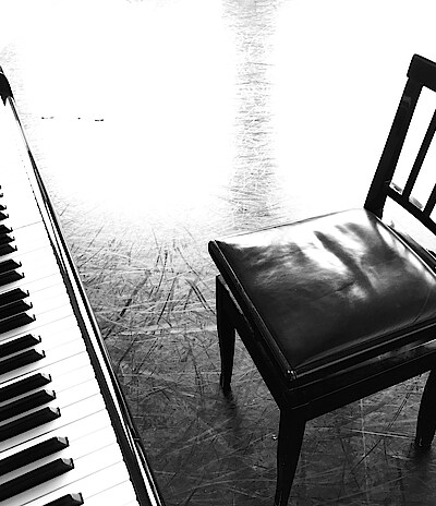 Klaviertasten und leerer Stuhl, in schwarz-weiß