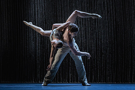 2 dancers before black background