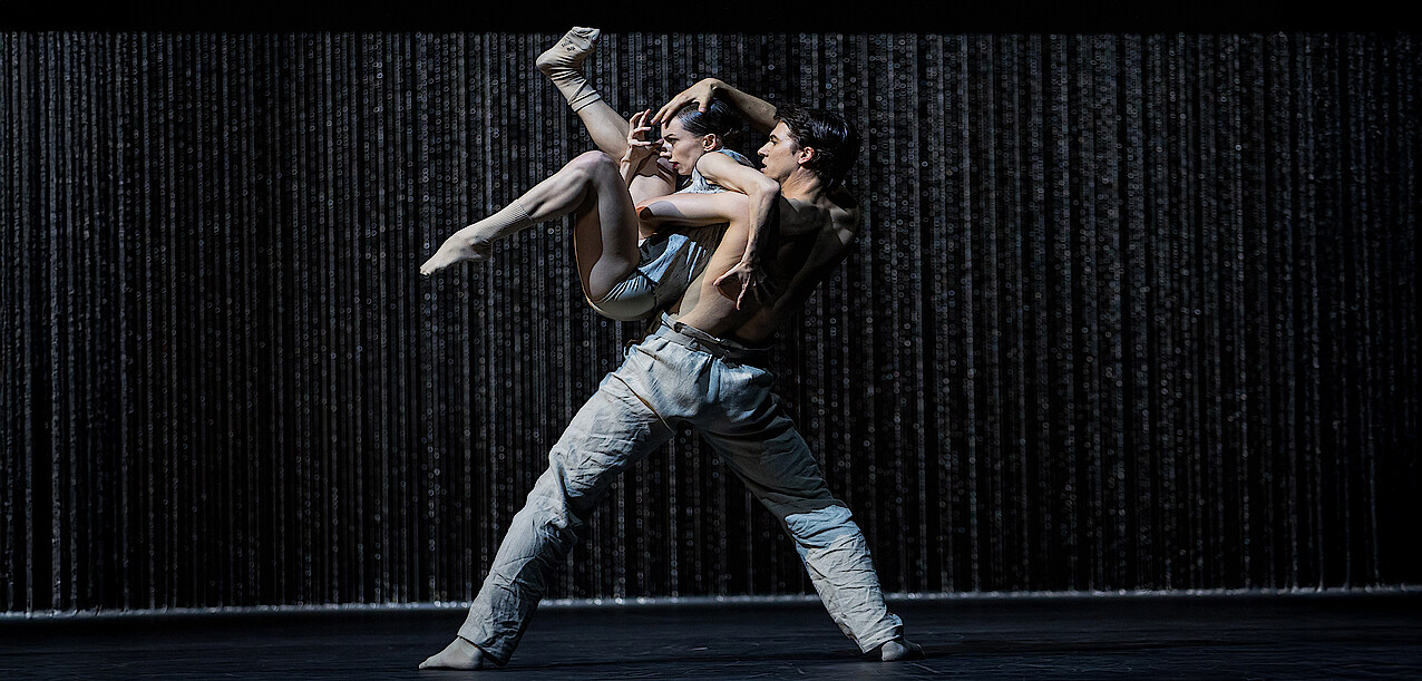 Martin ten Kortenaar und Fiona McGee tanzen vor einem Vorhang aus Metallketten.