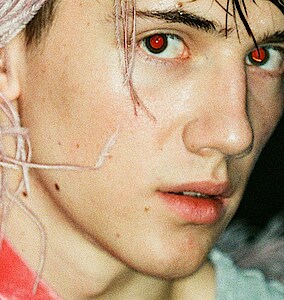 Tänzer Matthys de Beer trägt pinkfarbenen Federkopfschmuck und blickt verhalten in die Kamera.