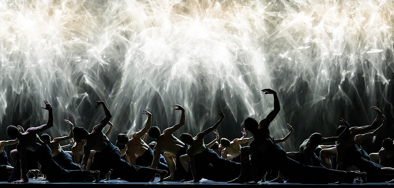 Ensemble in kniender Pose vor Lichtschauspiel.