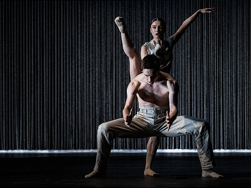 2 dancers before black background