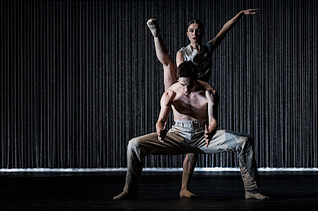 2 dancers before black background